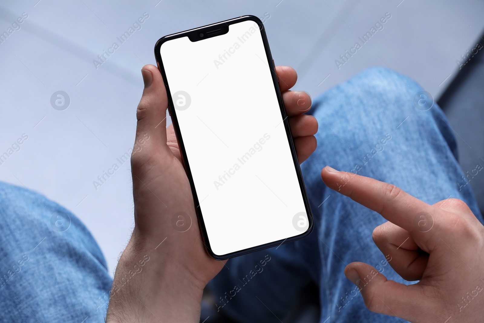 Photo of Man holding smartphone with blank screen indoors, closeup. Mockup for design