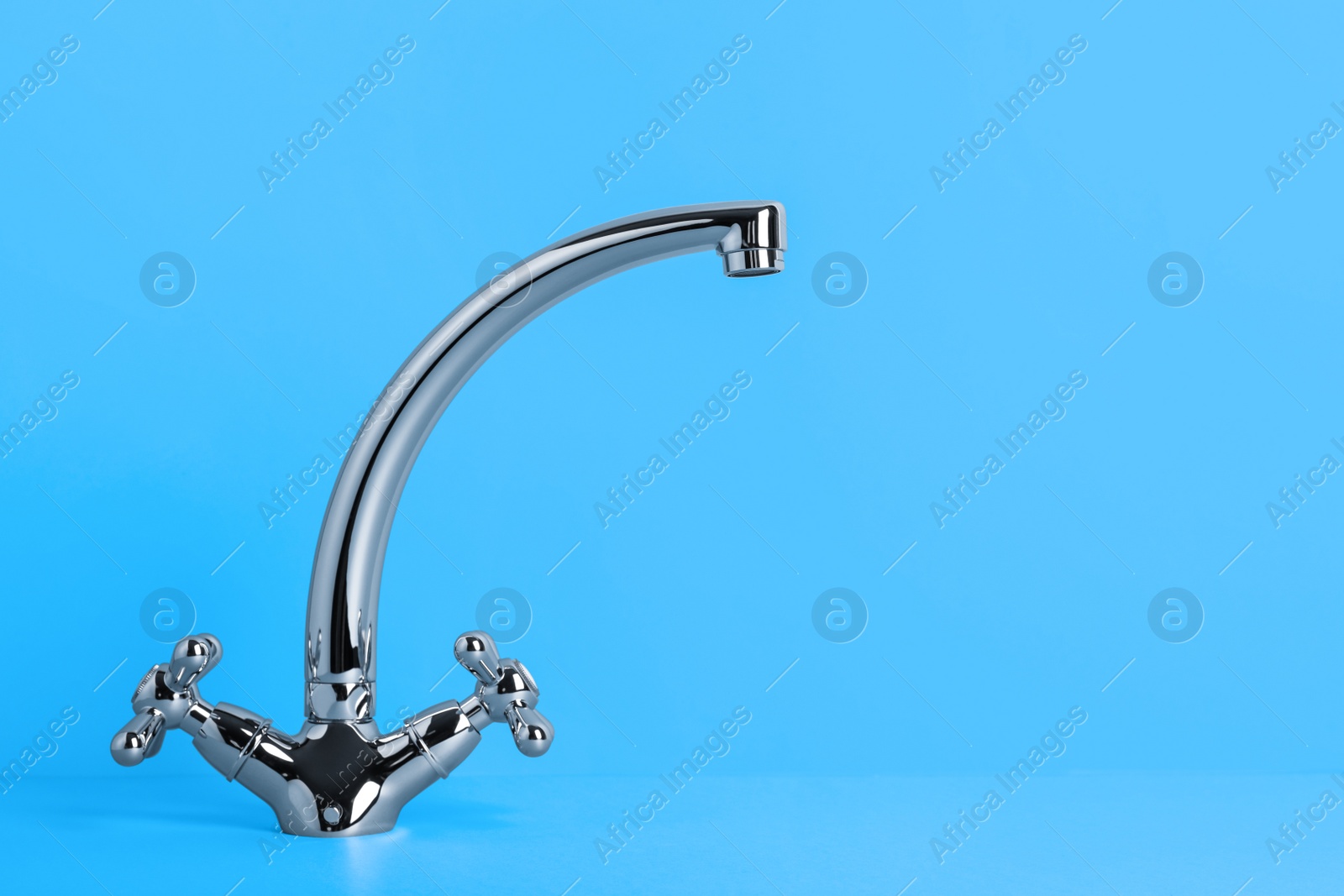 Photo of Double handle water tap on light blue background. Space for text