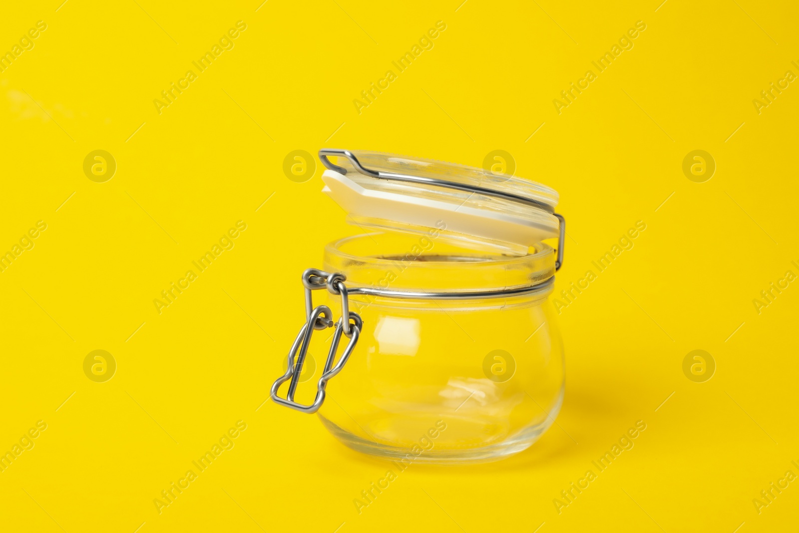 Photo of Open empty glass jar on yellow background
