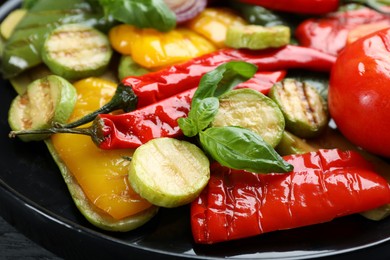 Photo of Delicious grilled vegetables on black plate, closeup