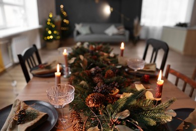 Dining table with burning candles and Christmas decor in stylish room. Interior design