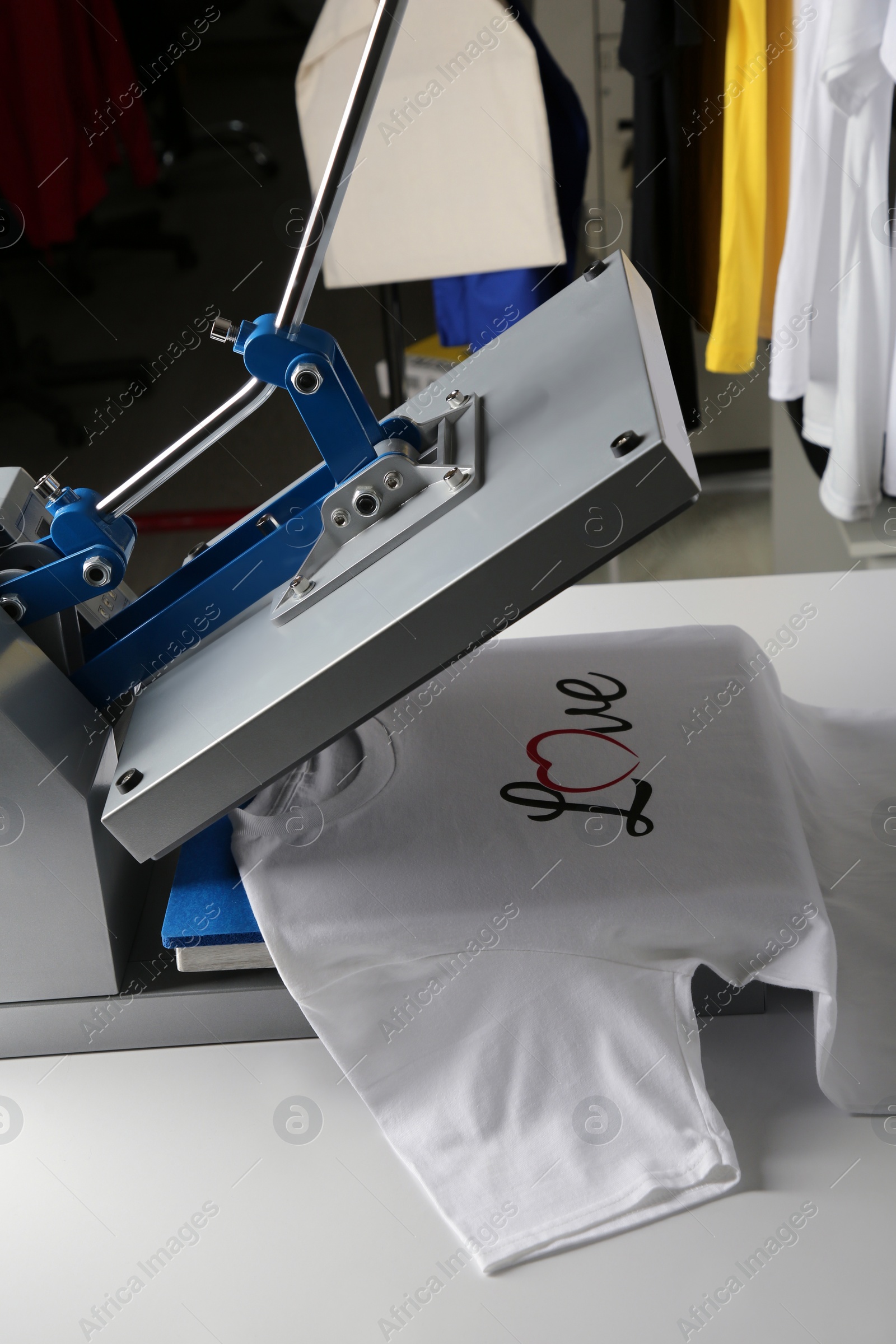 Photo of Printing logo. Heat press with t-shirt on white table