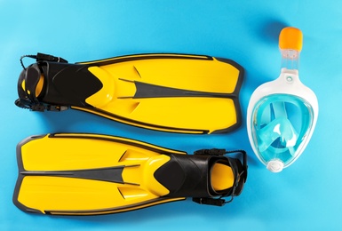 Pair of yellow flippers and diving mask on color background, top view