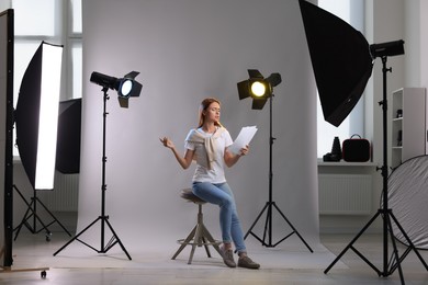 Photo of Casting call. Emotional woman with script performing on grey background in modern studio