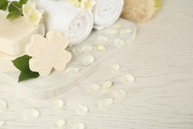 Photo of Beautiful jasmine flowers, towels and soap bars on white wooden table