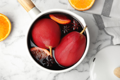 Image of Poaching pears in mulled wine on white marble table, flat lay