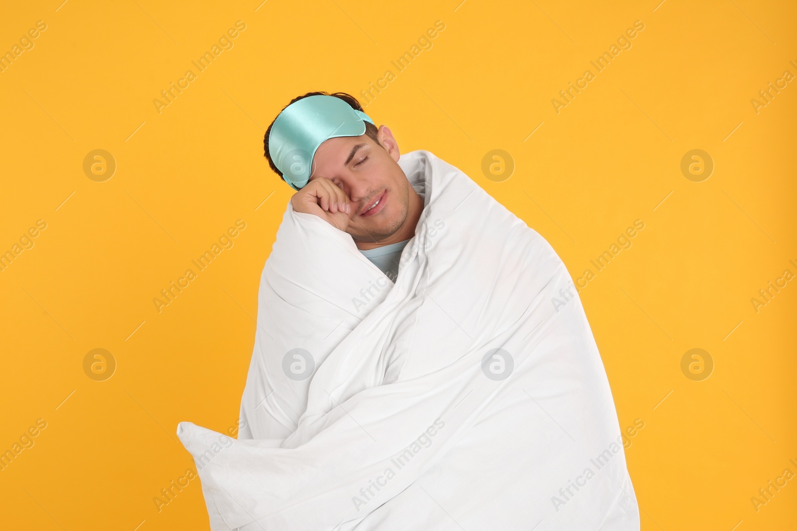 Photo of Man wrapped with blanket in sleeping mask on yellow background