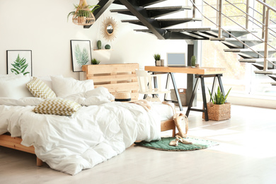 Photo of Elegant interior of bedroom with workplace under stairs