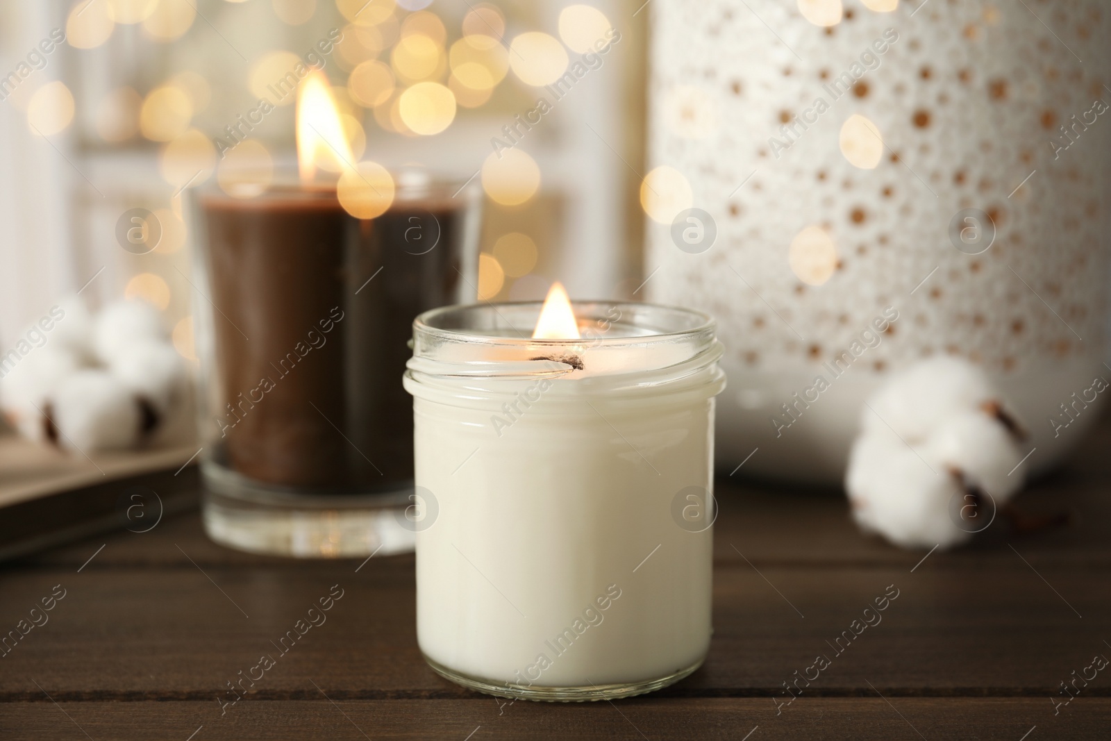 Photo of Burning candles in glass holders on wooden table