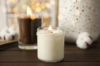 Burning candles in glass holders on wooden table