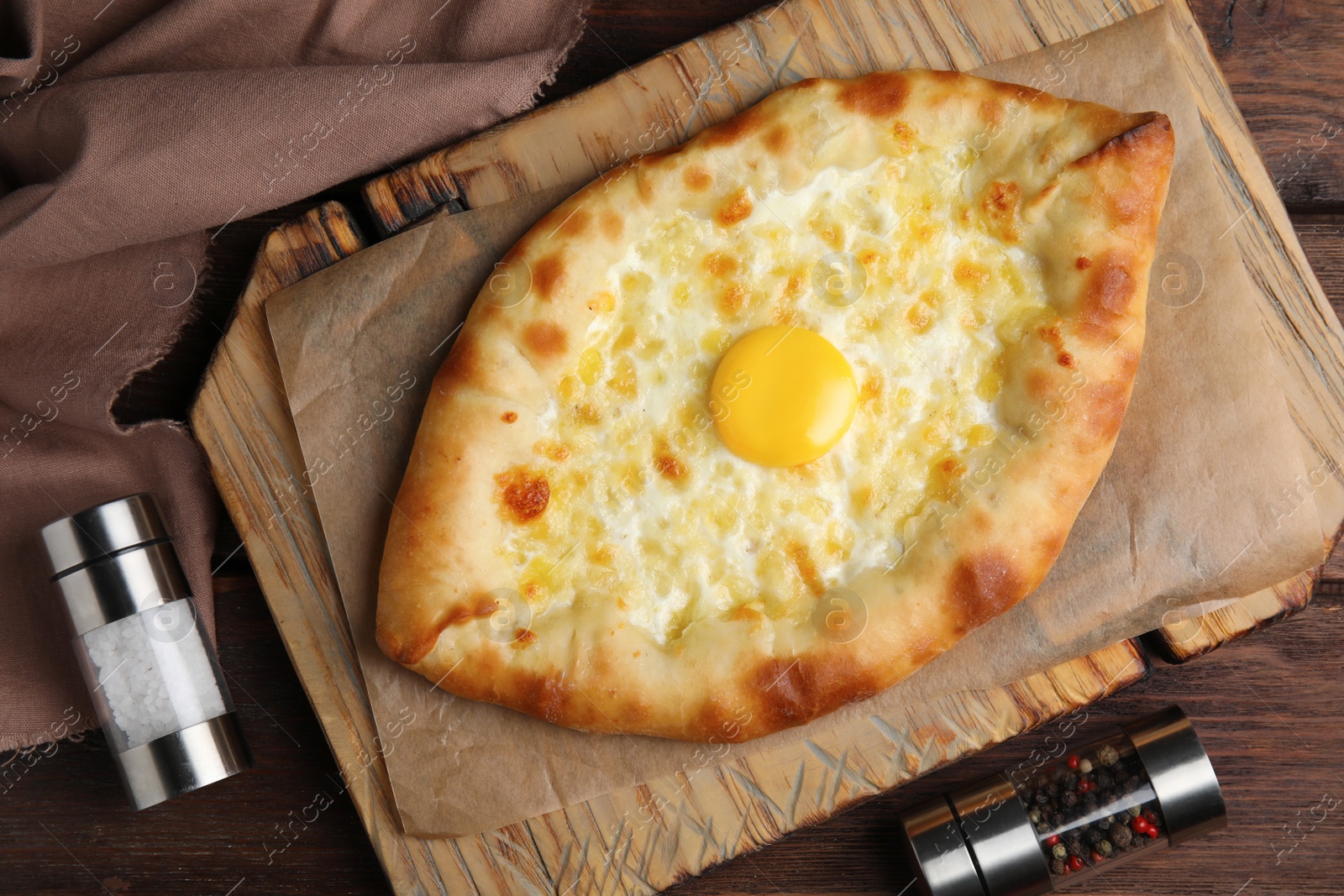 Photo of Fresh homemade khachapuri with cheese and egg on wooden table, flat lay