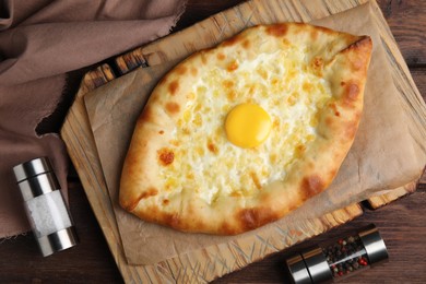 Photo of Fresh homemade khachapuri with cheese and egg on wooden table, flat lay