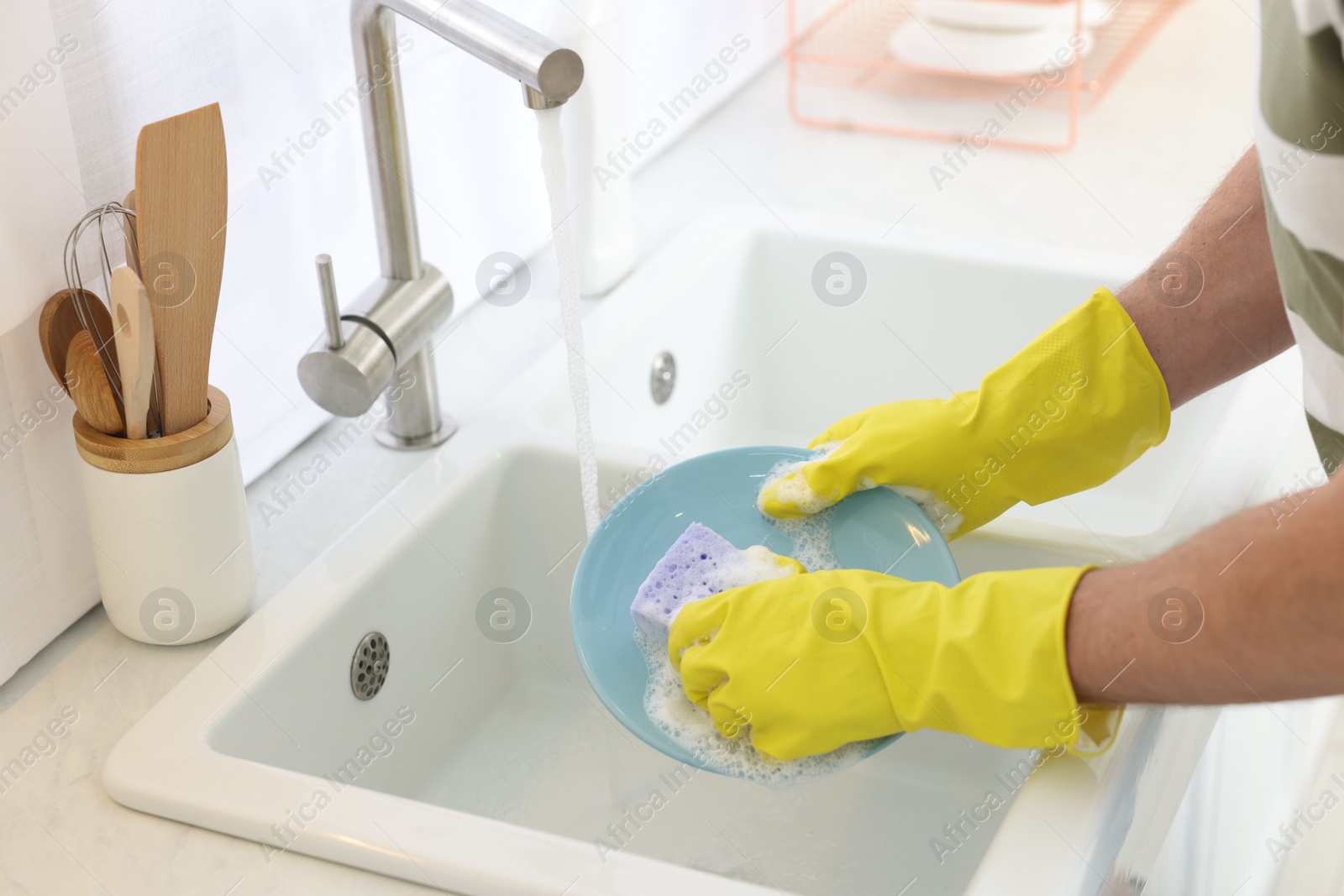 Photo of Man washing plate above sink in kitchen, closeup