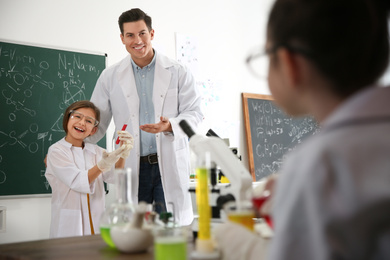 Photo of Teacher with pupil at chemistry lesson in classroom