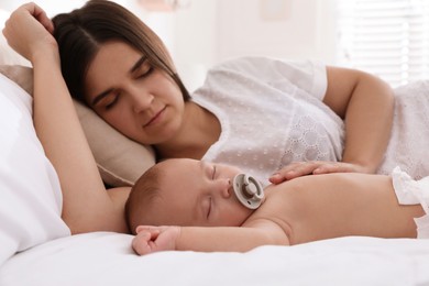 Mother with her cute baby sleeping in bed at home