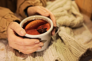 Photo of Woman with cup of mulled wine at table, closeup
