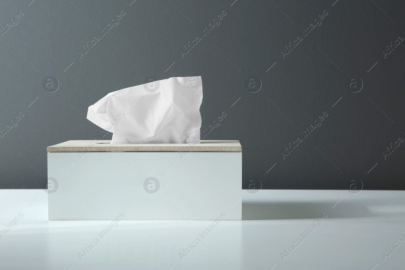 Photo of Holder with paper tissues on white table. Space for text