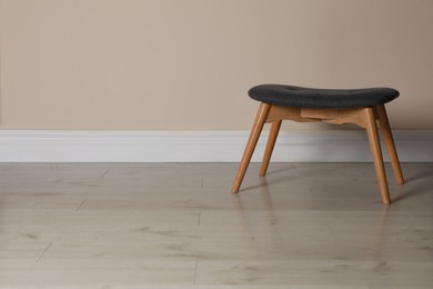 Photo of Stylish stool near beige wall indoors. Space for text