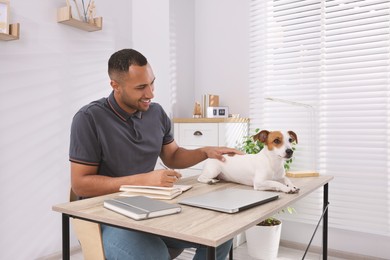 Photo of Young man with Jack Russell Terrier at desk in home office