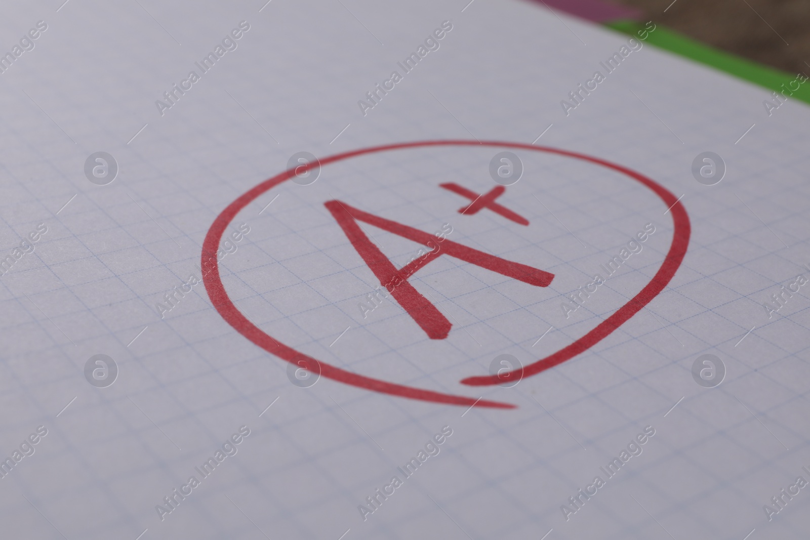 Photo of School grade. Red letter A with plus symbol on notebook paper, closeup