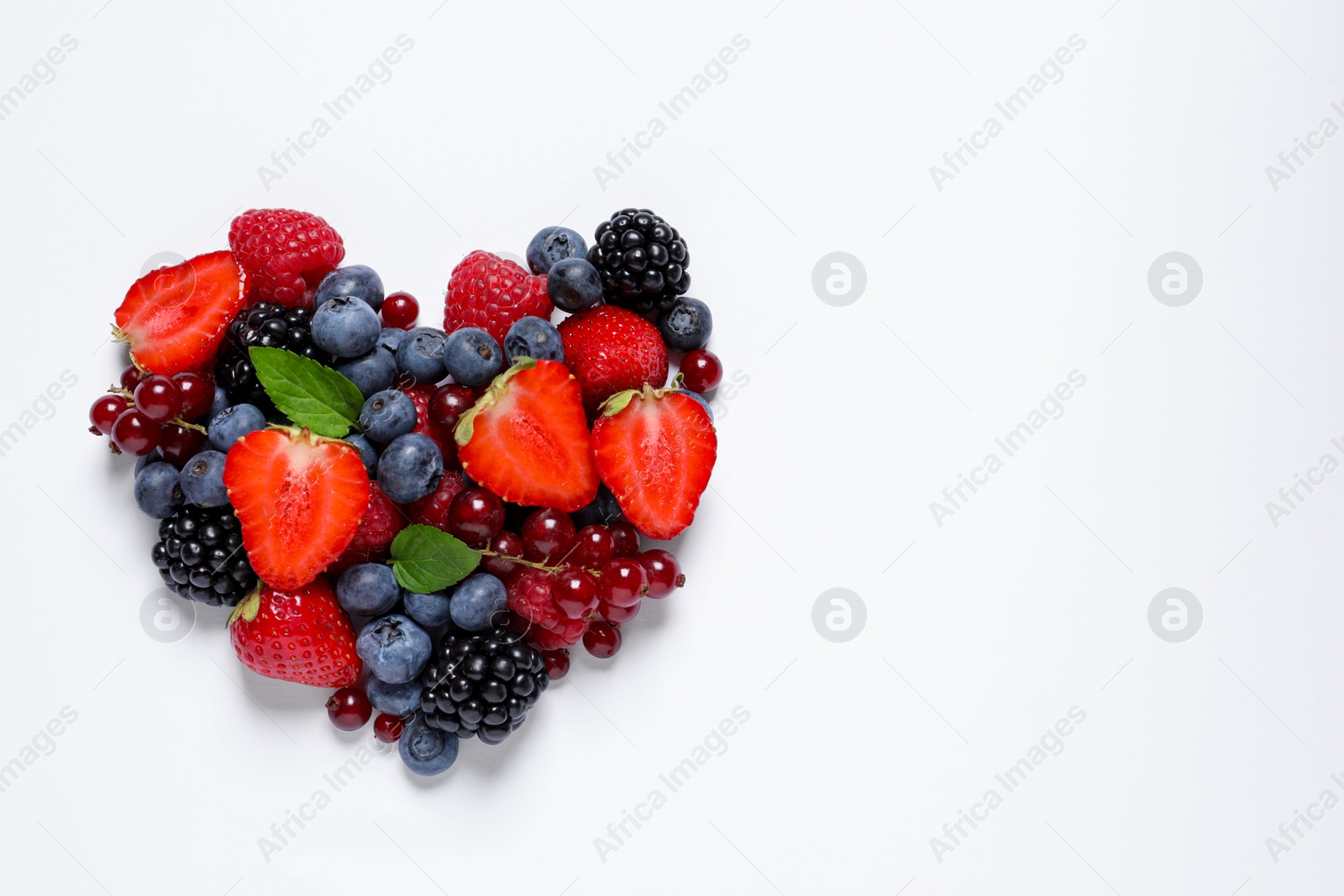 Photo of Heart made of different fresh ripe berries on white table, top view. Space for text