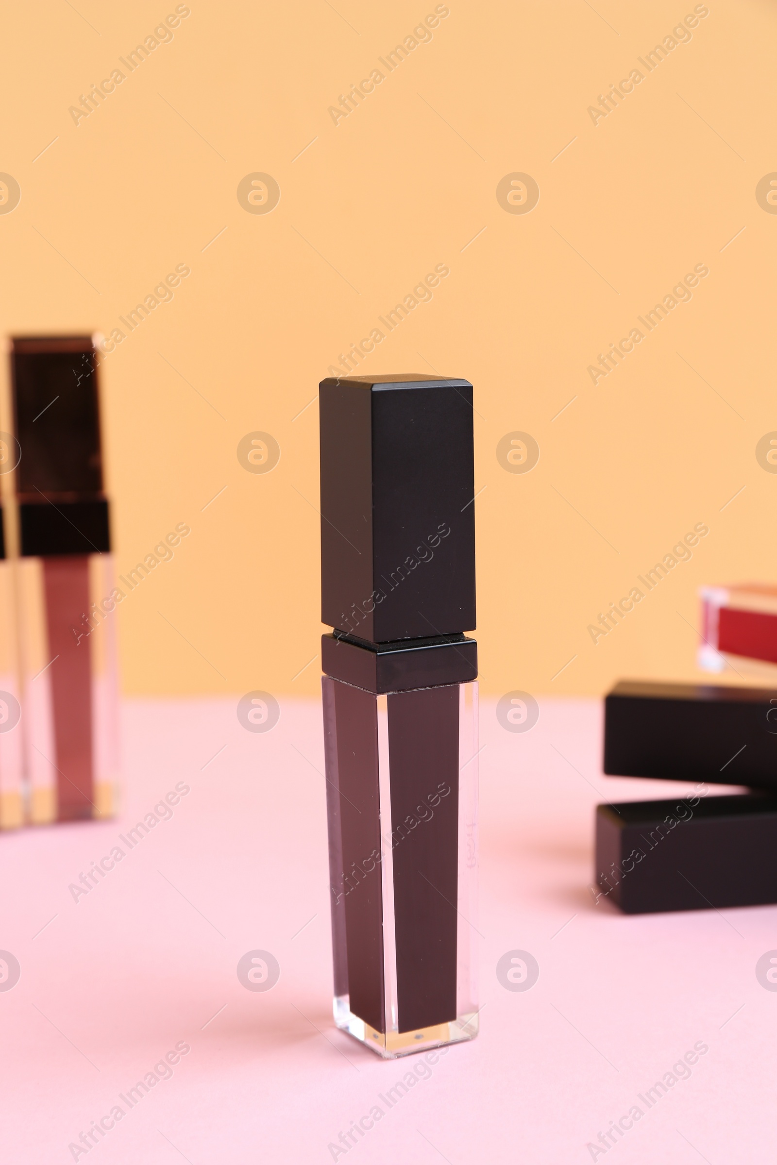 Photo of Many different lip glosses on color background