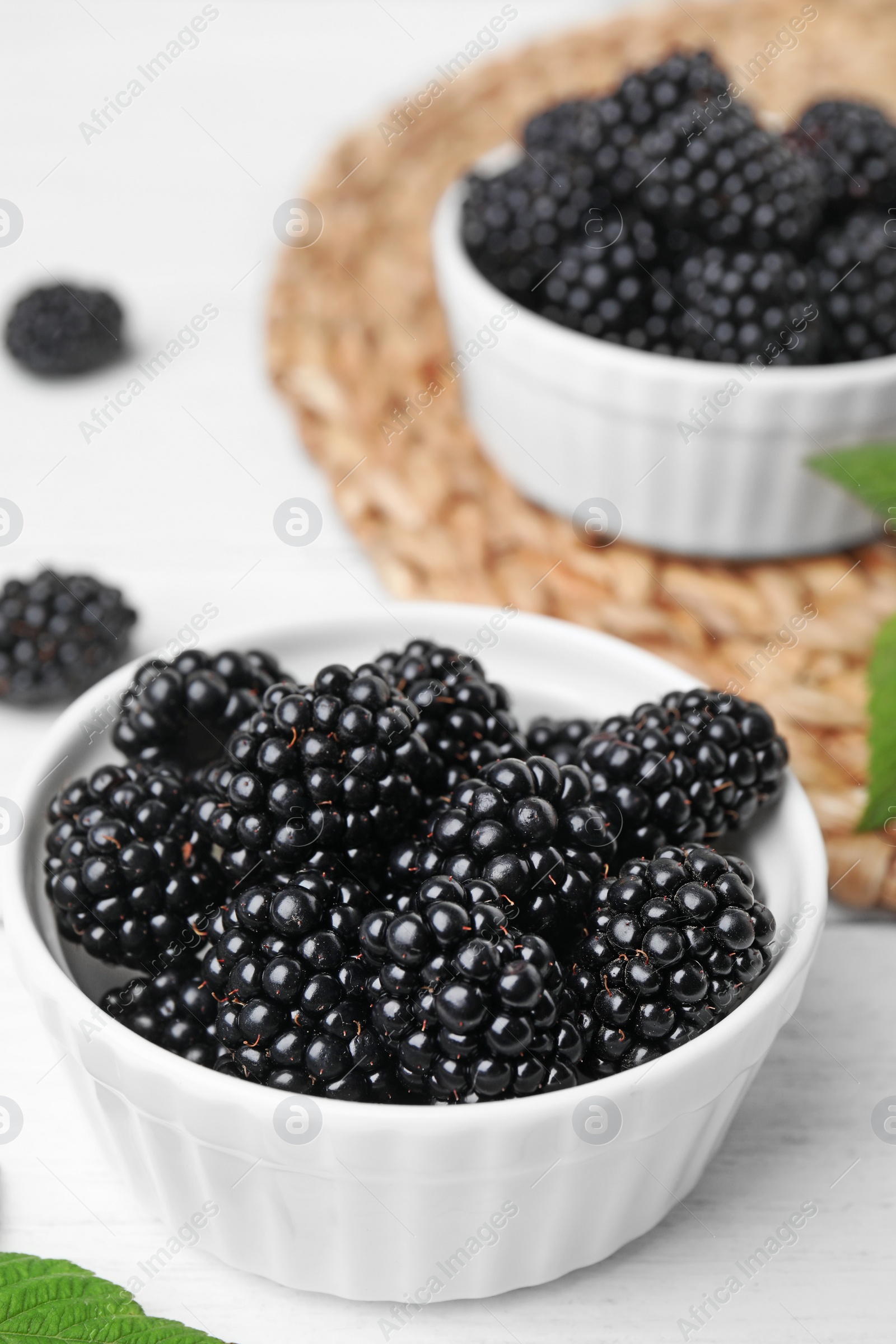 Photo of Bowls of tasty blackberries on white wooden table