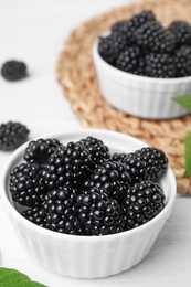 Photo of Bowls of tasty blackberries on white wooden table