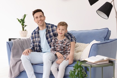 Photo of Dad and his son sitting on sofa at home