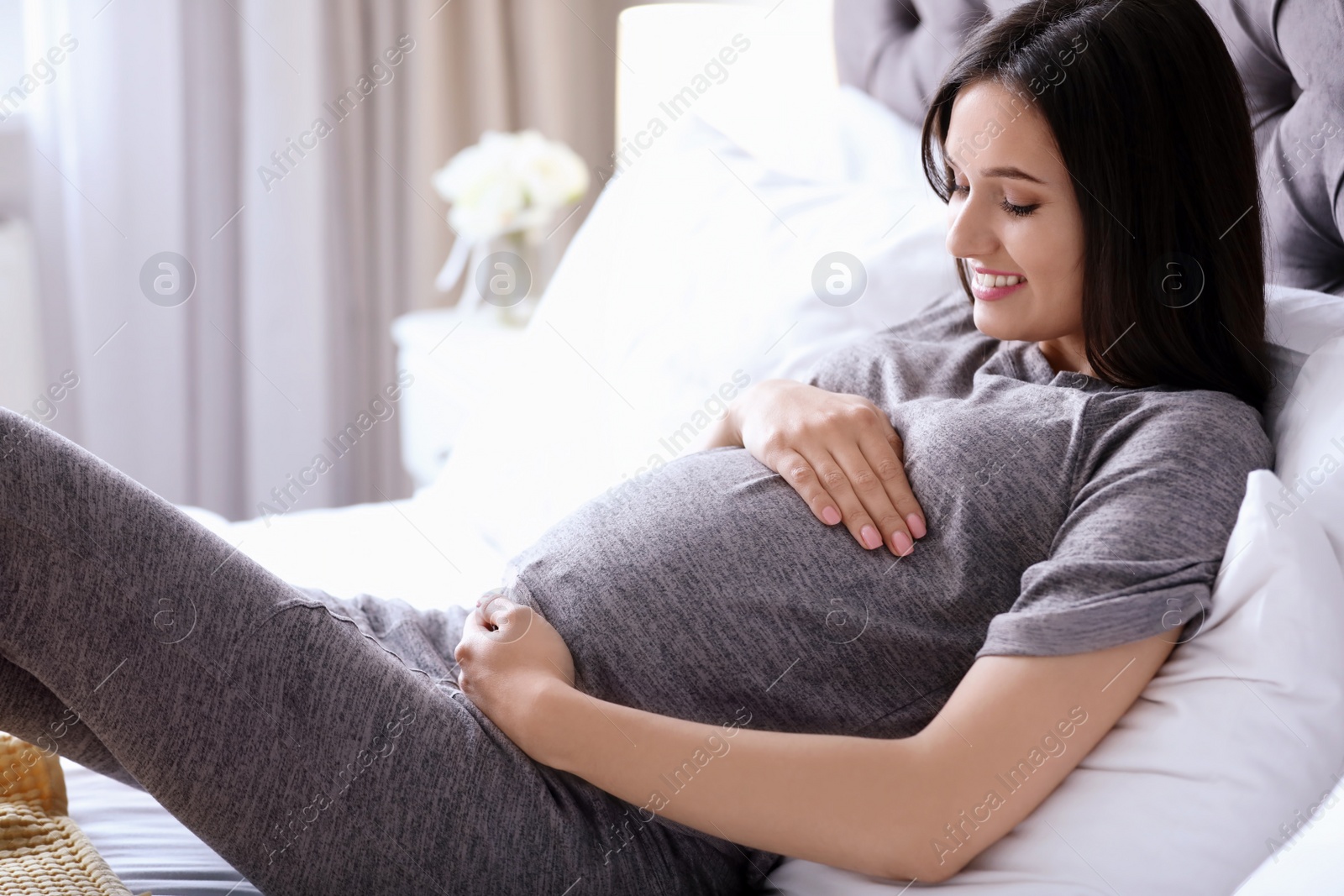 Photo of Young pregnant woman lying on bed at home