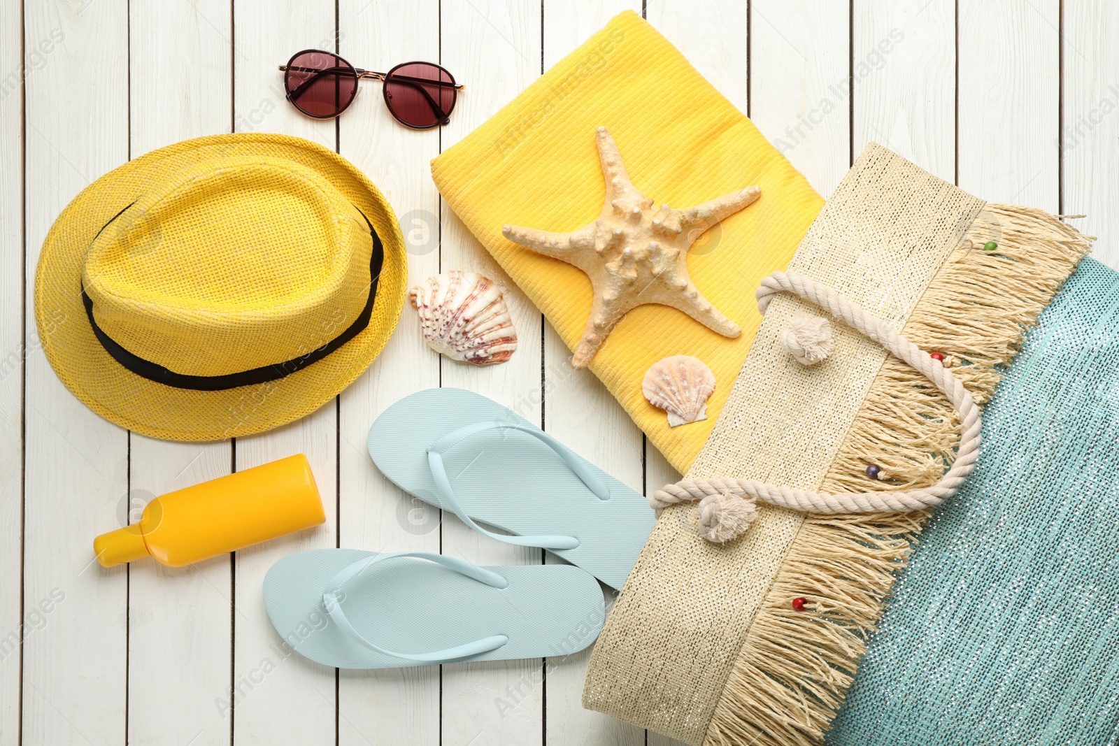 Photo of Stylish bag and beach accessories on white wooden background, flat lay