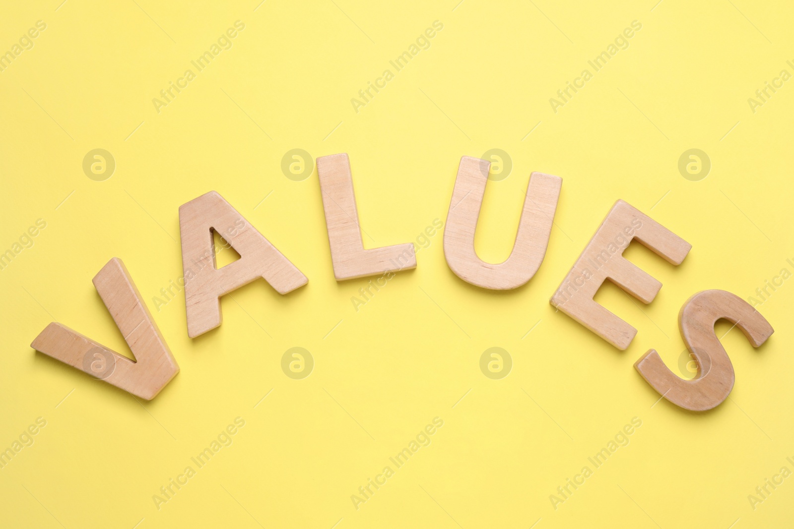 Photo of Word VALUES made of wooden letters on yellow background, flat lay
