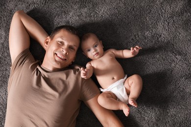 Happy man with his cute baby on floor, top view