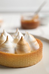 Photo of Tartlet with meringue on white plate, closeup. Delicious dessert
