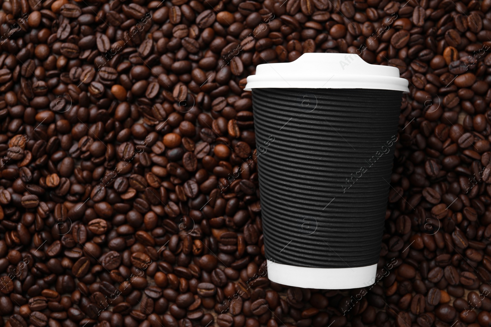 Photo of Coffee to go. Paper cup on roasted beans, top view and space for text