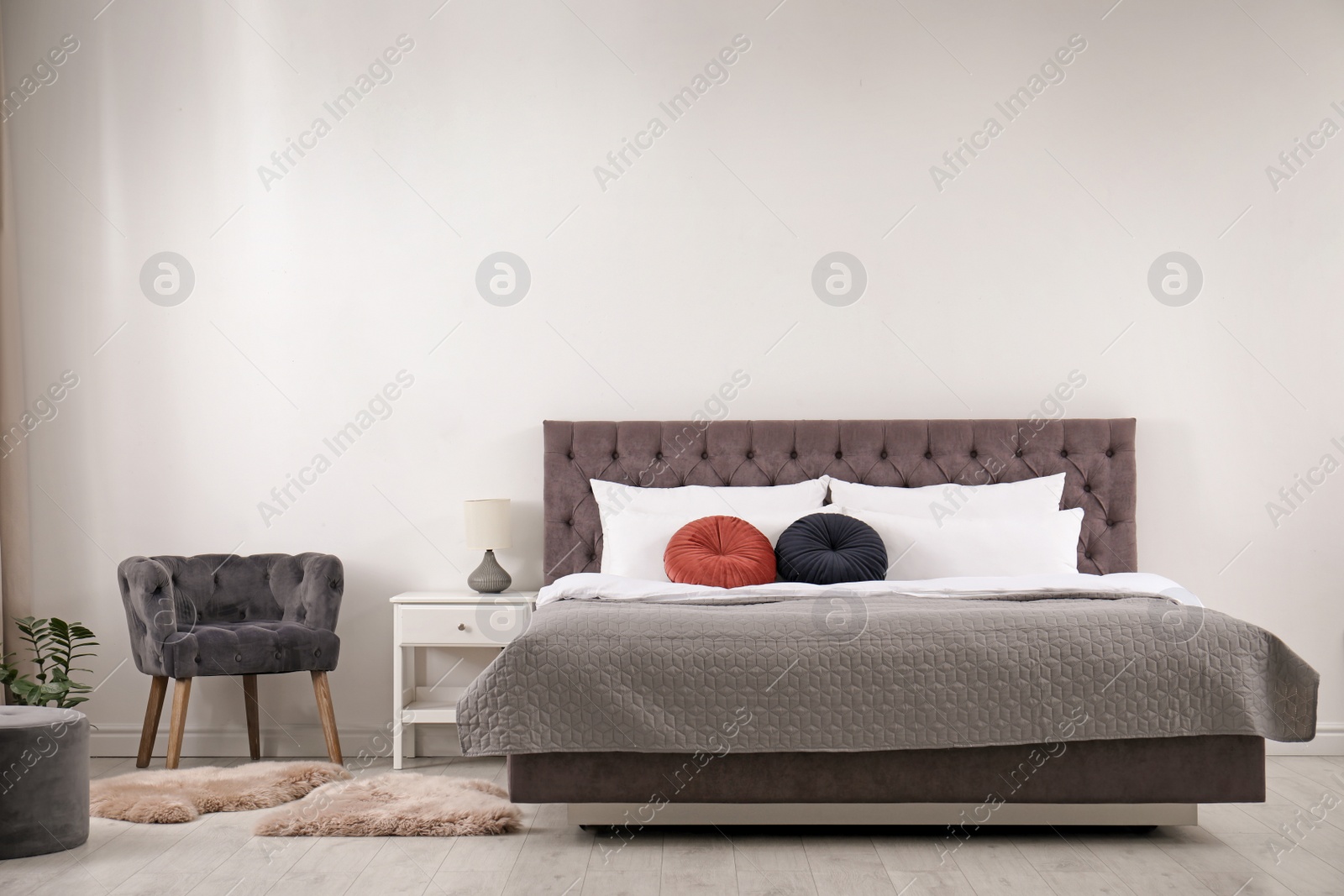 Photo of Large comfortable bed near light wall in simple room interior