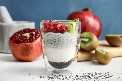 Photo of Glass of tasty chia seed pudding with kiwi and pomegranate on table