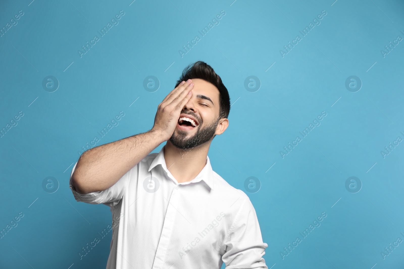 Photo of Young man laughing on light blue background. Funny joke