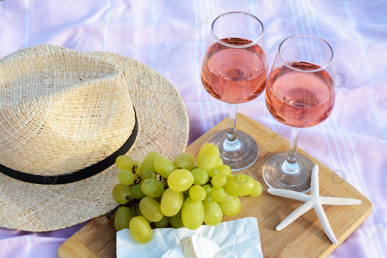 Photo of Glasses with rose wine and snacks on picnic blanket