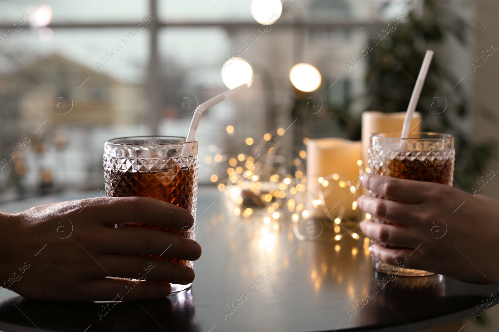 Photo of Couple with glasses of cold cola at table in cafe, closeup