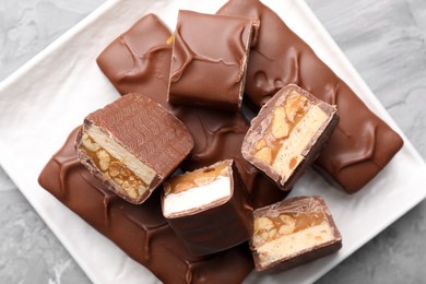 Photo of Tasty chocolate bars with nougat, caramel and nuts on table, top view