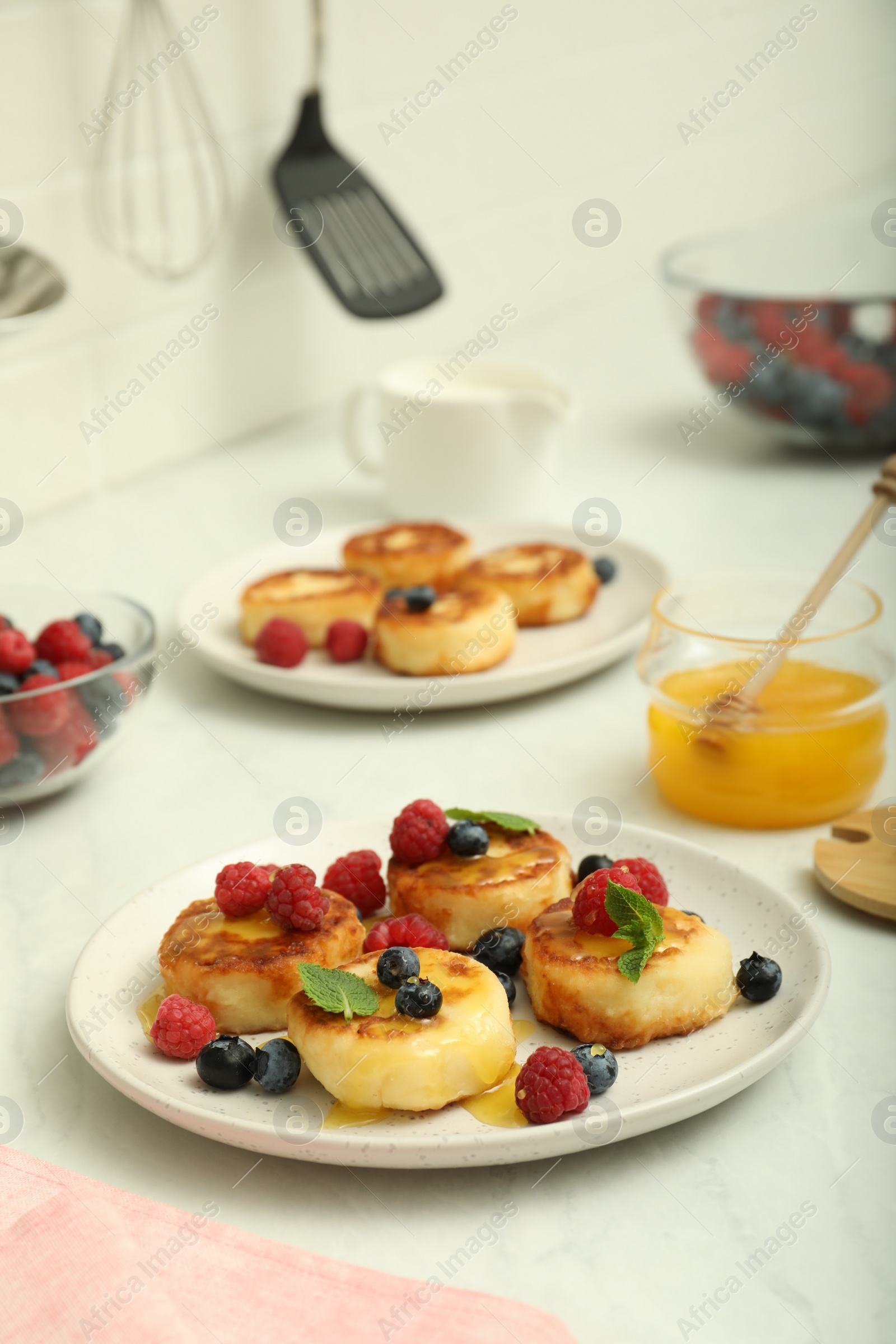 Photo of Delicious cottage cheese pancakes with fresh berries and mint on white countertop