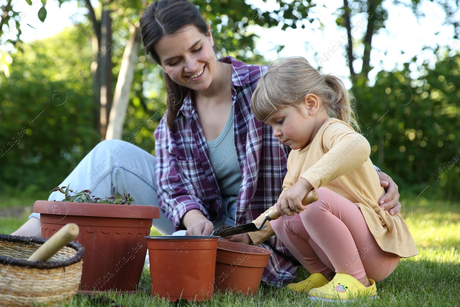 Photo of Mother and her daughter planting tree together in garden