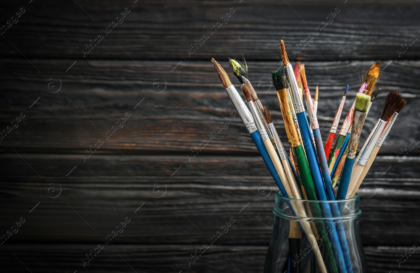 Photo of Jar with paint brushes on wooden background. Space for text