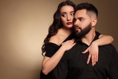 Photo of Handsome bearded man with sexy lady on light brown background. Space for text