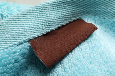 Photo of Clothing label on light blue fluffy towel, closeup