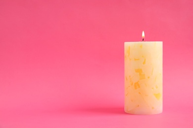 Alight wax candle on color background. Space for text