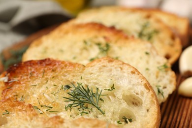 Photo of Tasty baguette with garlic and dill on wooden tray, closeup