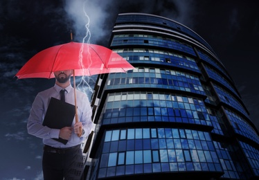 Businessman with umbrella in city center. Insurance concept