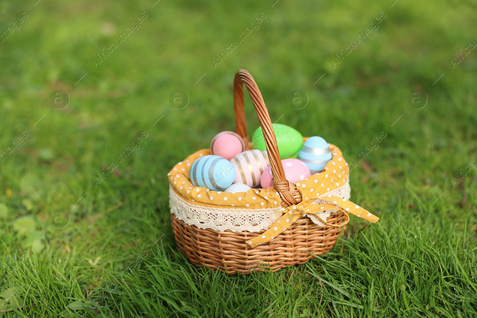 Photo of Easter celebration. Painted eggs in wicker basket on green grass